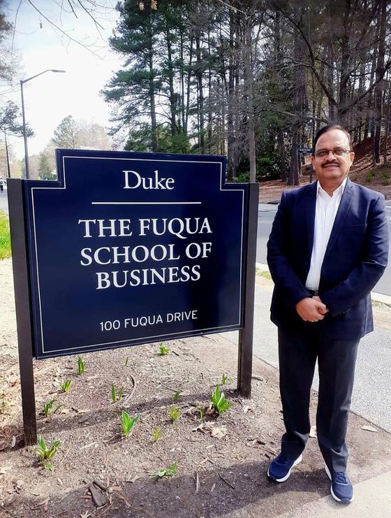 Dr Hegde beside the sign of The Fuqua School of Business, Duke University
