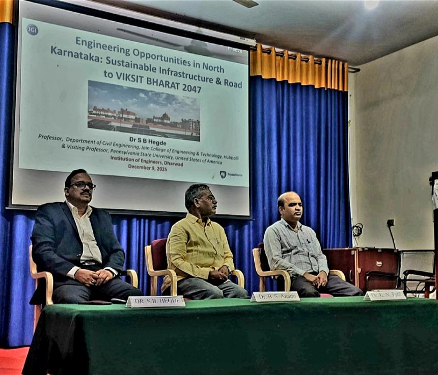 Dr Hegde seated on the dais beside two speakers, below a projected slide titled Engineering Opportunities in North Karnataka