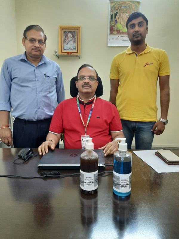 Dr Hegde seated at his desk with two colleagues