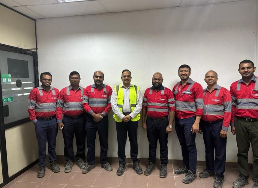 Dr Hegde in a safety vest with a plant team in red uniforms